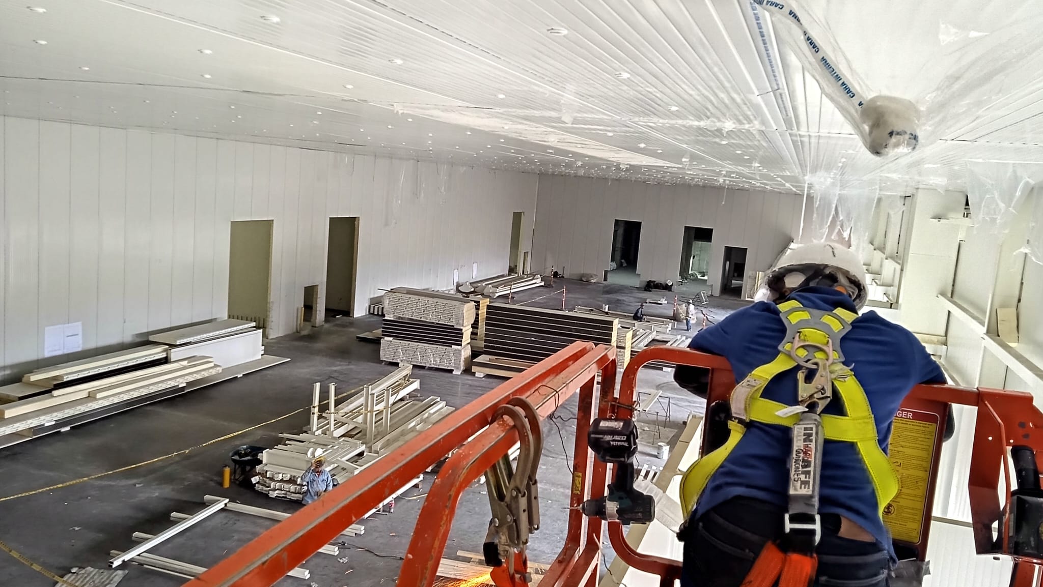 Equipo de instaladores en plataforma elevadora dentro de una superficie industrial